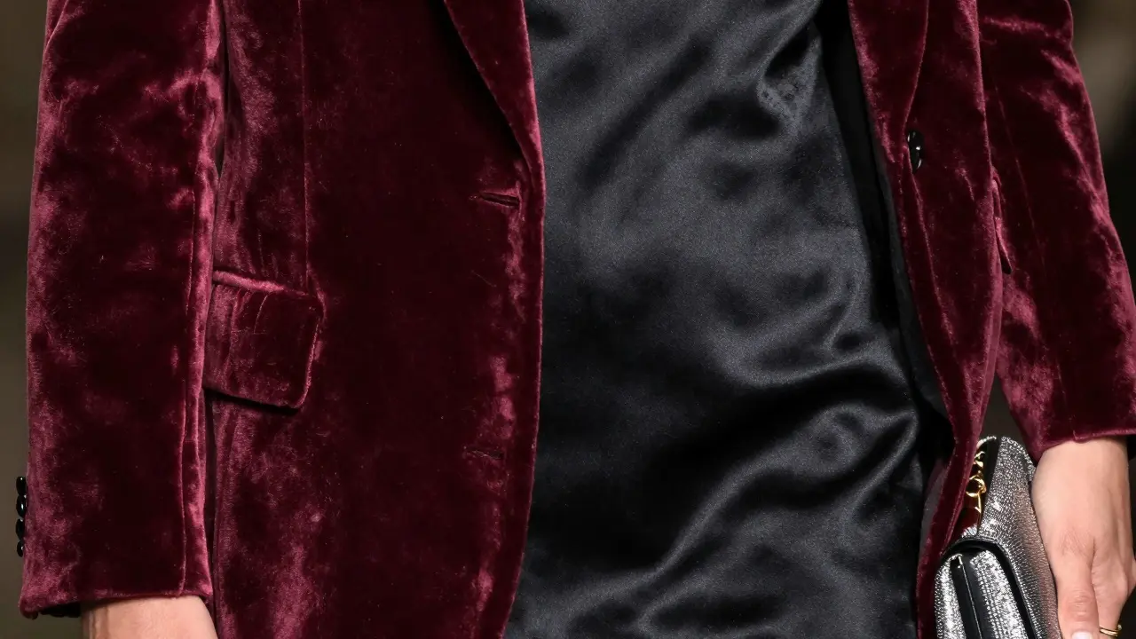 Close-up of burgundy velvet and black satin fabrics with a metallic clutch bag.